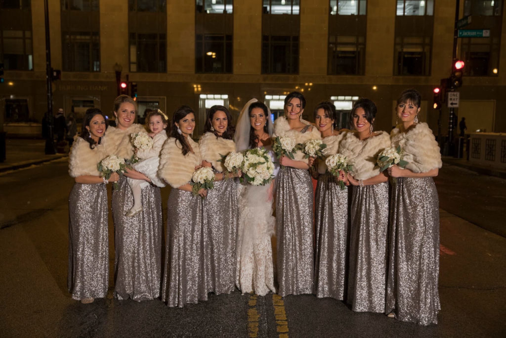 Bride with bridesmaids posing outside on a cold night.