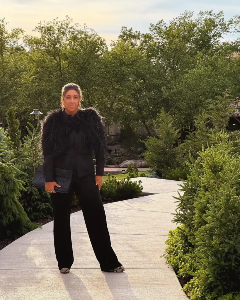 Michelle Durpetti wearing all black attire, featuring black feathers in the should areas, posing for a portrait outdoors during Engage 24 luxury wedding business summit.