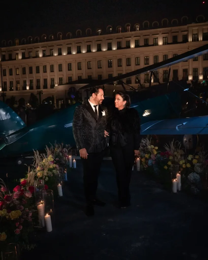 Collin Pierson and Michelle Durpetti looking at eachother while posing in front of an aircraft and floral arrangements with candles.