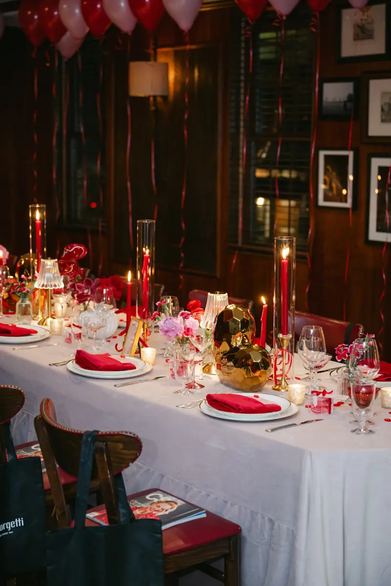 A chic and romantic Galentine’s dinner setup featuring red and gold accents, elegant candles, floral arrangements, and festive décor in a cozy, intimate setting.